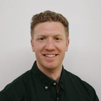 Dr Colin Sylvester has short ginger hair. he is wearing a dark shirt and smiling at the camera